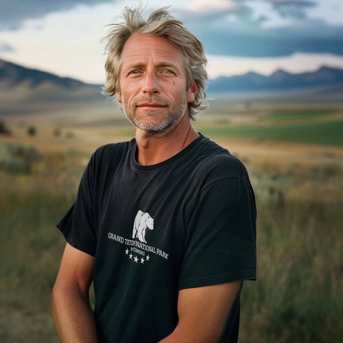 A man wearing a black shirt with a grizzly bear on the front, with the words Grand Teton National Park, Wyoming