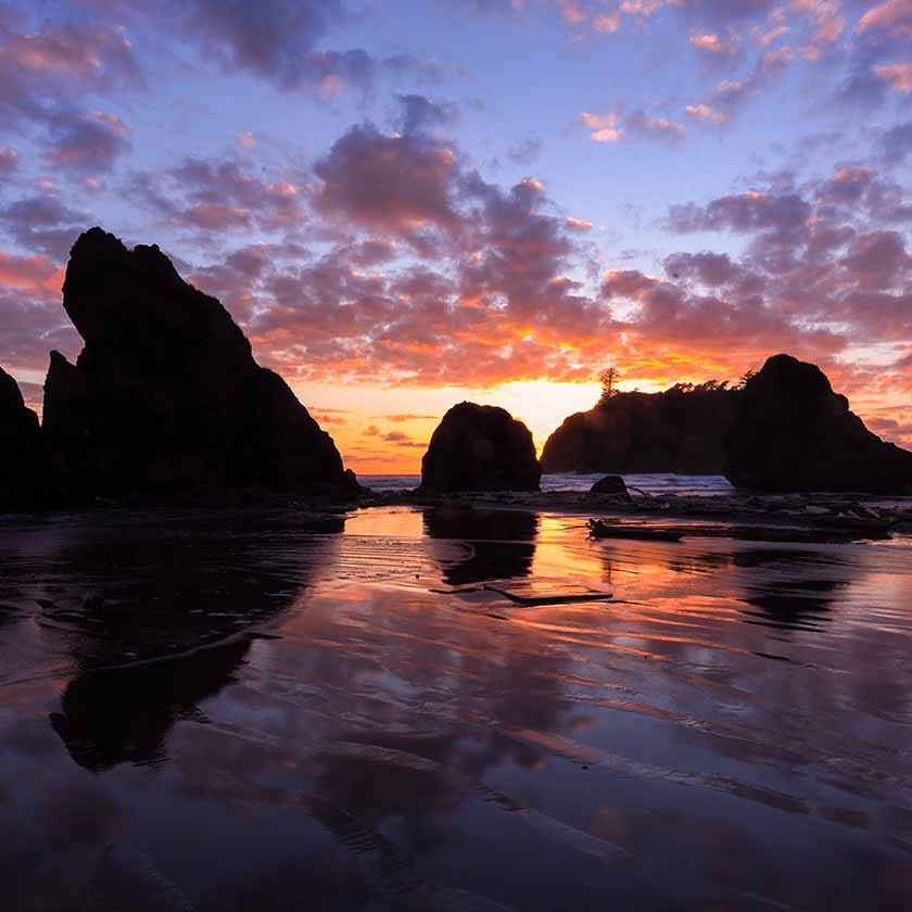 Rocks silhouetted against a sunset on the beach